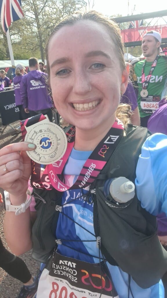 Steph from The Grand Appeal running with her London Marathon medal.