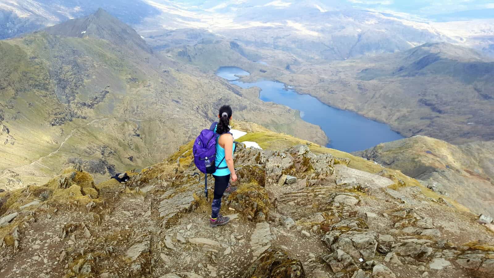 A woman looking into the distance as she climbs a mountain.