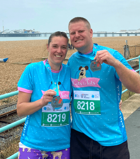 Two people holding race medals.