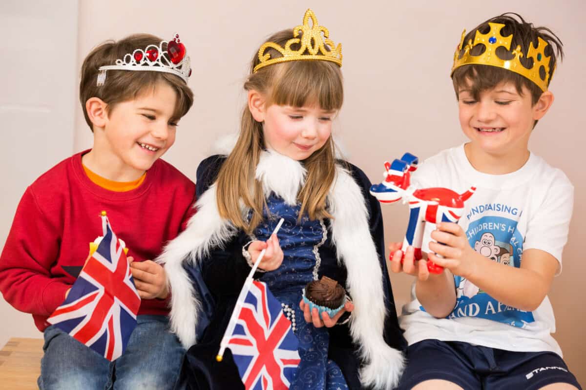 Three children eating jubilee themed cupcakes and playing with a Gromit figurine.