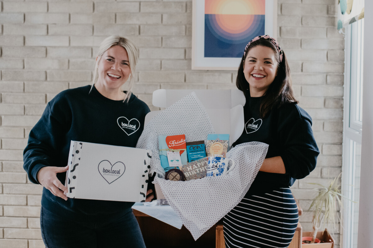 Two people holding a gift hamper.