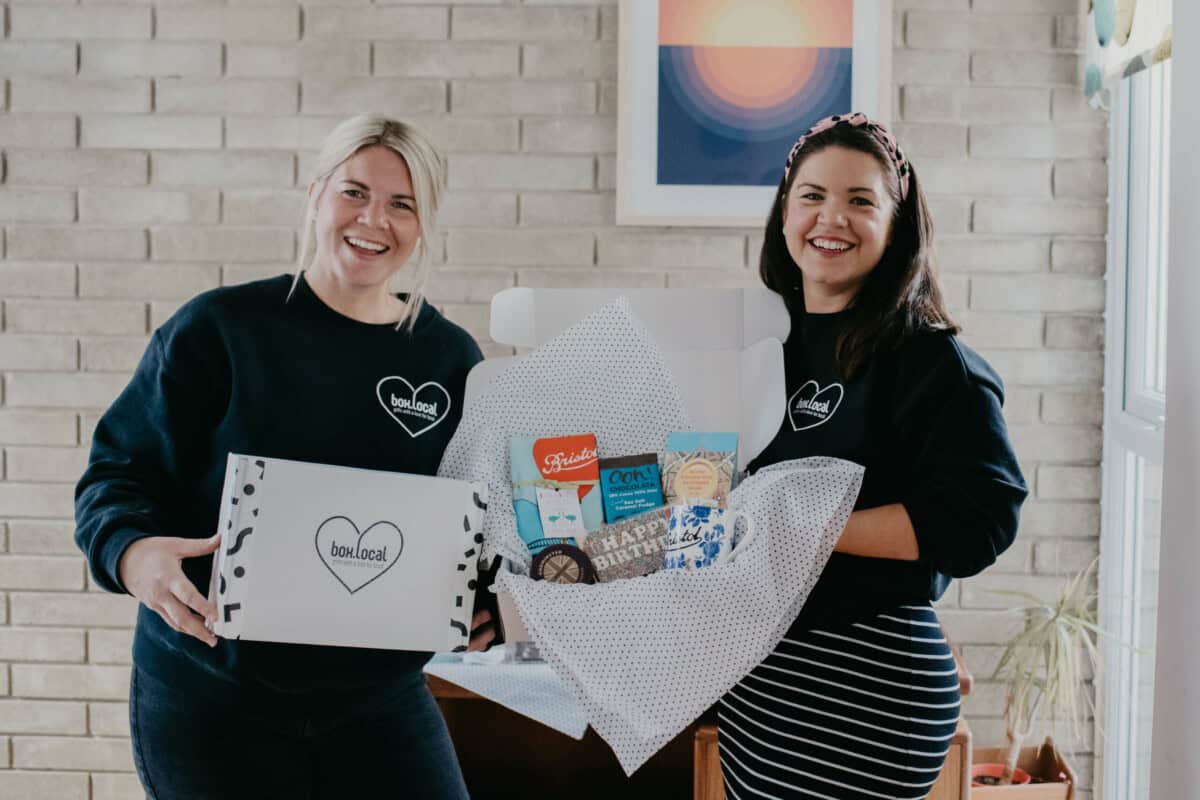 Two people holding a gift hamper.