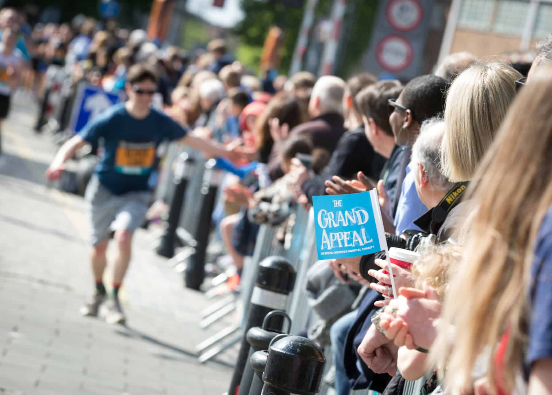 Individual running the Great Bristol Run as he high-fives spectators.