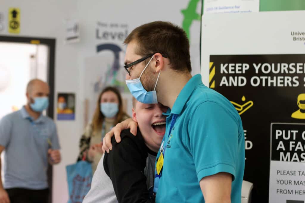 Jayden, a patient at Bristol Children's Hospital, hugging a member of staff and smiling.