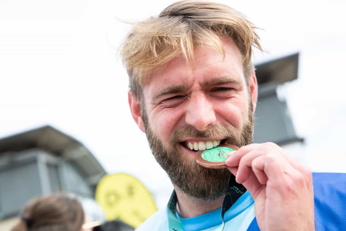 man biting his great bristol run medal