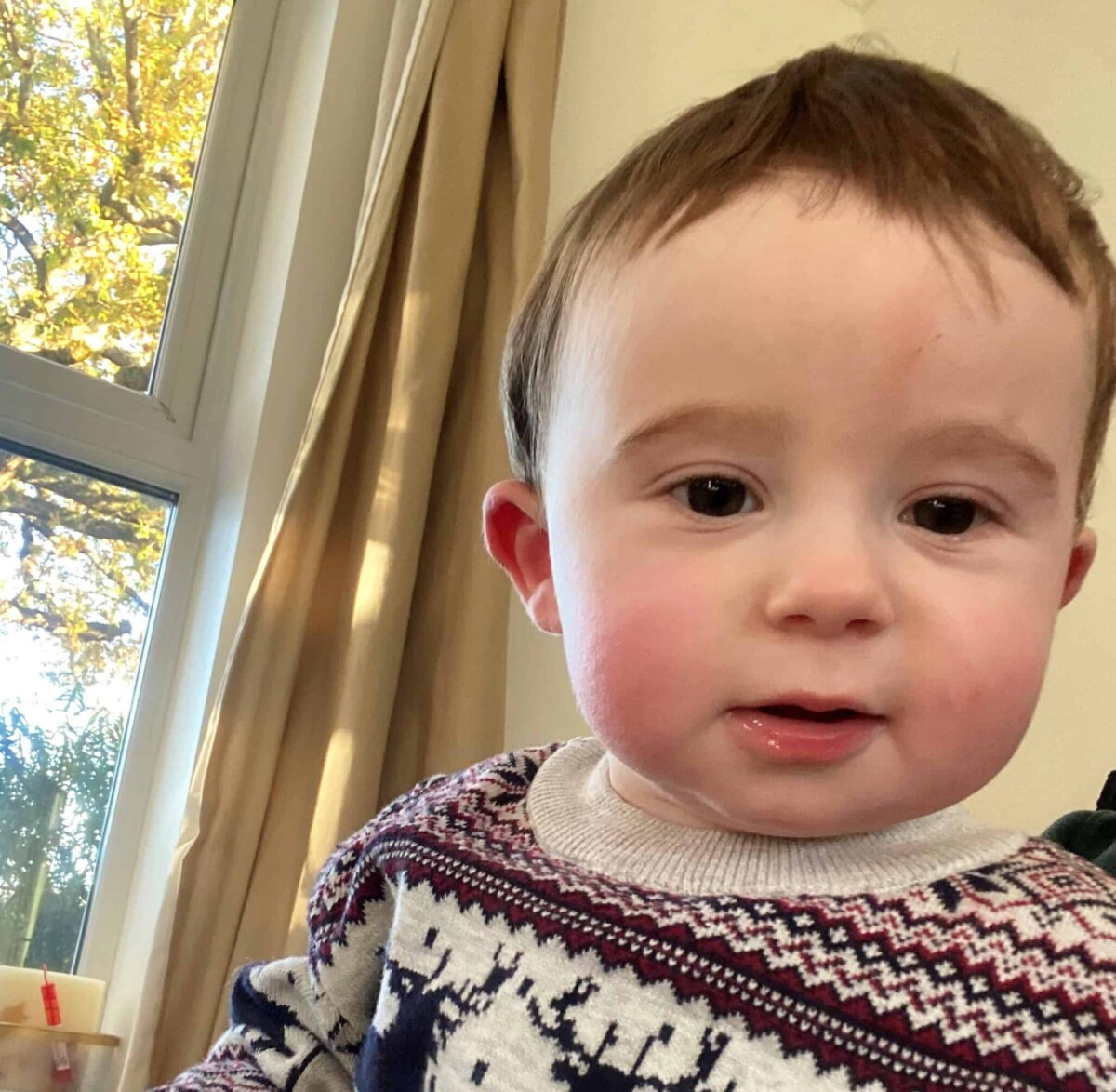 Toddler who is wearing a jumper looking into the camera