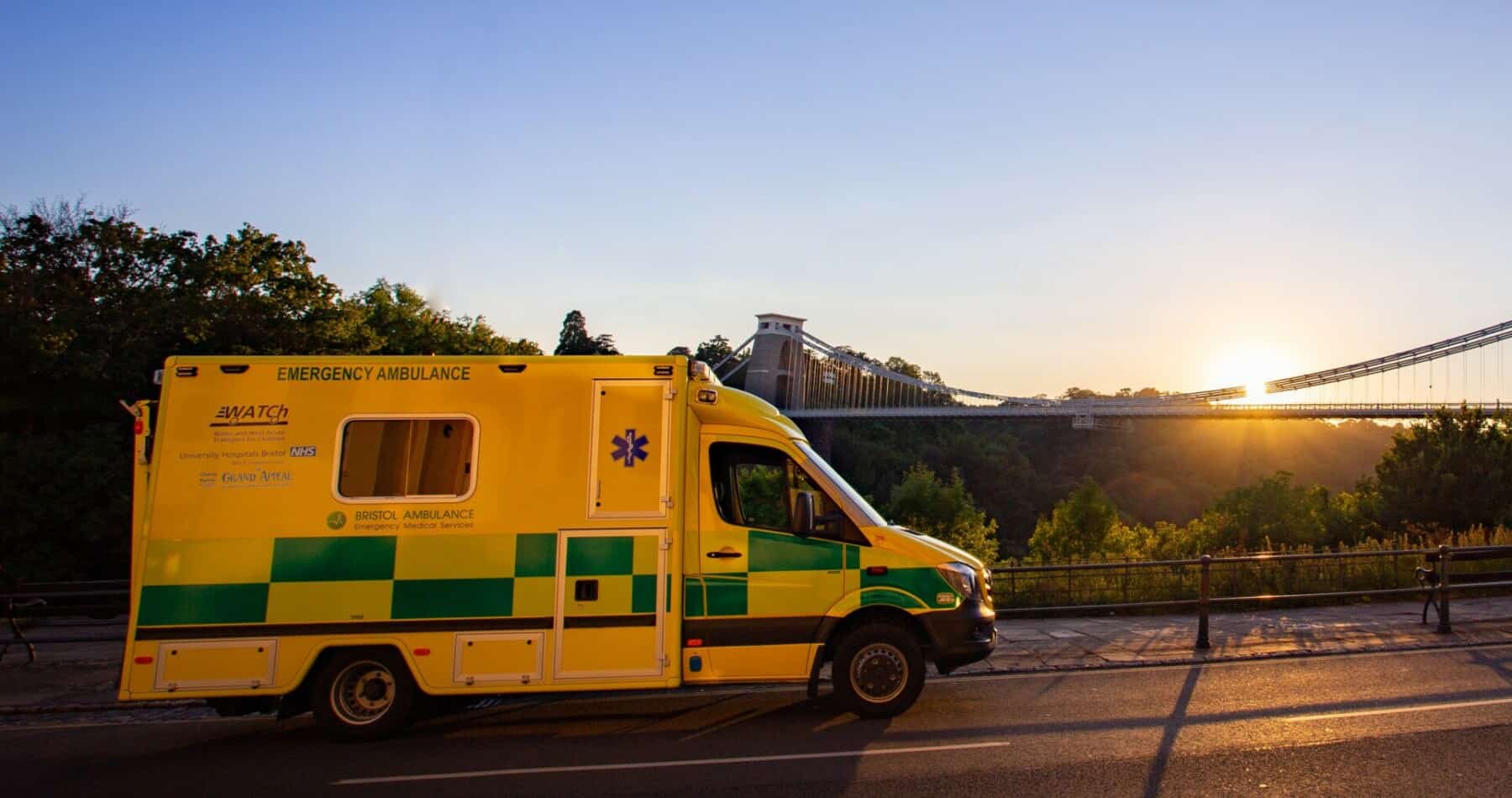 An ambulance parked on a road in front of a bridge