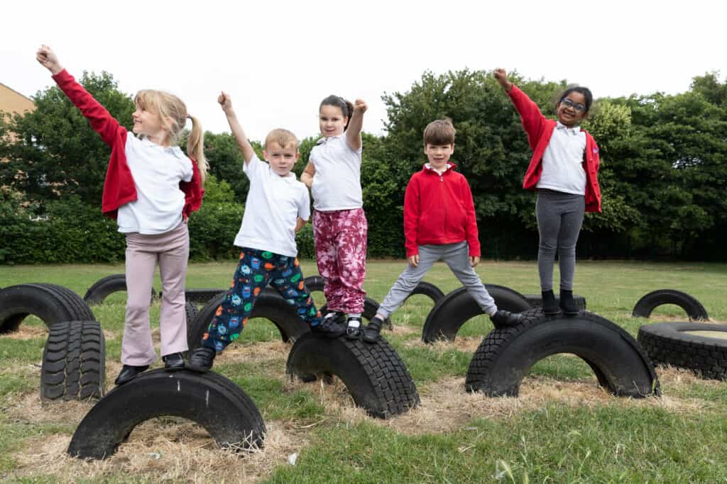 A group of children standing on tires in a school playground.