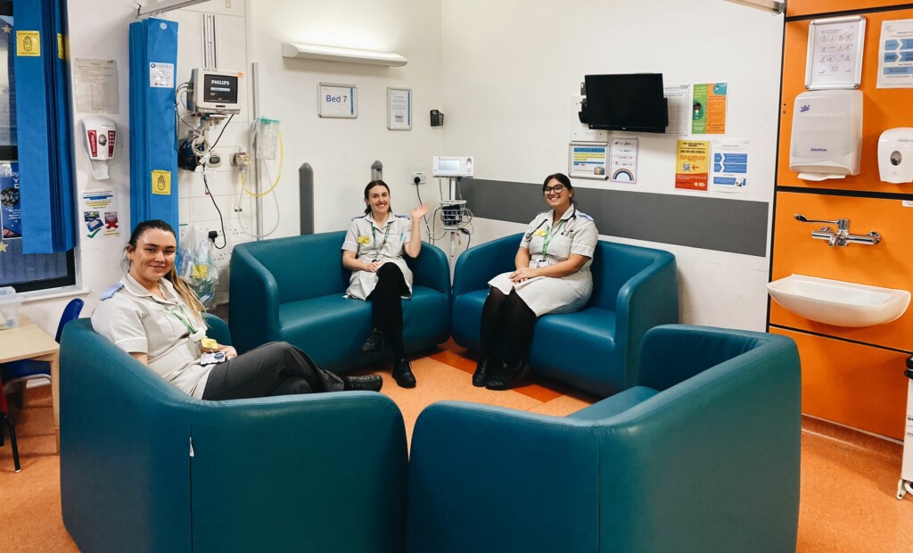 Three members of hospital staff sat on green sofas smiling