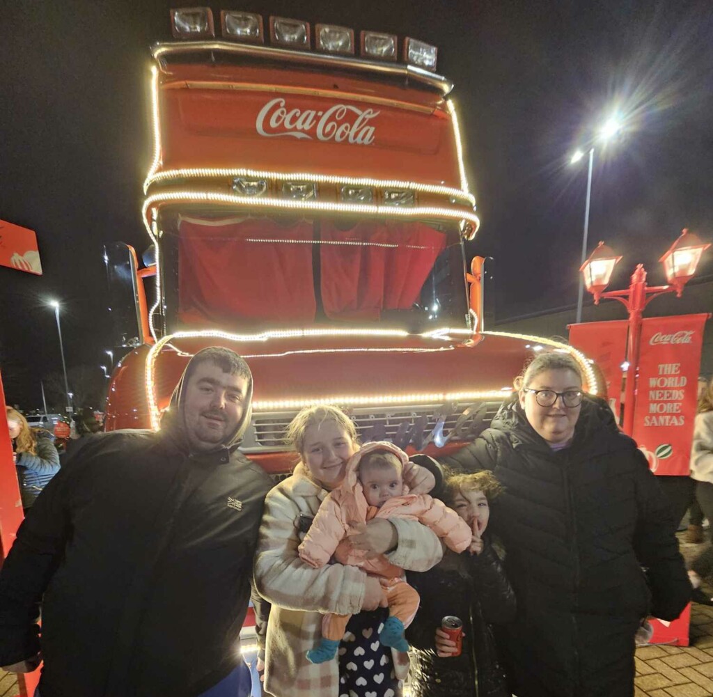 Lenny-Rose and her two sisters, mum and dad in front of the Christmas Coca Cola lorry