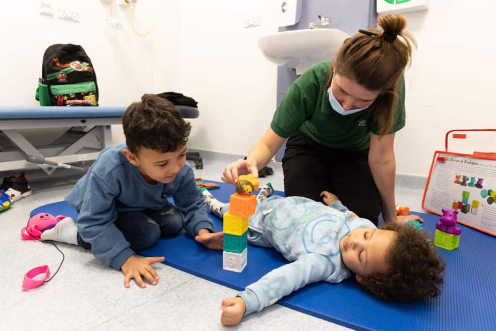 Two small boys playing with toys alongside a Play Assistant in Bristol Children's Hospital.