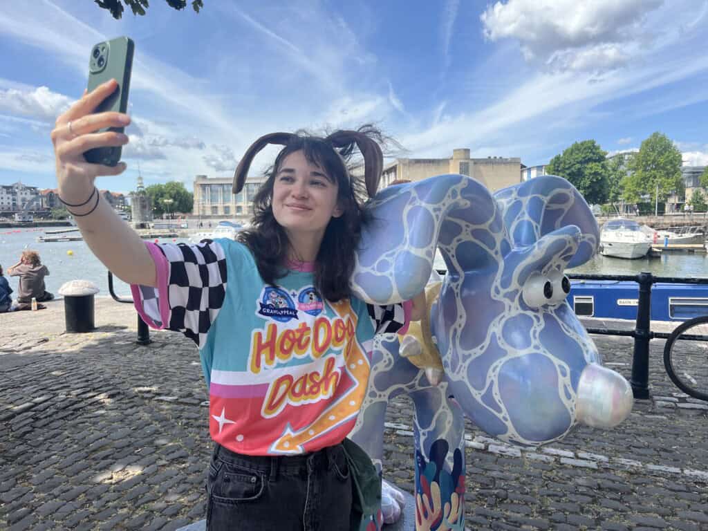 Fundraiser stops to take selfie with a Gromit sculpture during their 'Hot Dog Dash' challenge.