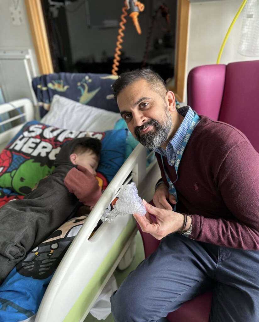 Dr Shafi Mussa holds a 3D-printed heart next to Miles' hospital bed.